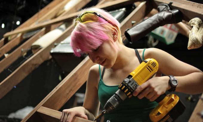 Woman building theatre sets with drill